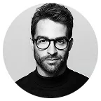 Black and white portrait of a man with glasses wearing a black turtleneck.